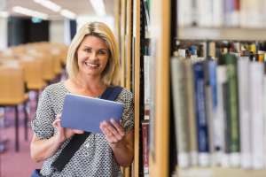 Top 7 Mobile Apps for Healthcare Travelers young woman smiling with a tablet in hand