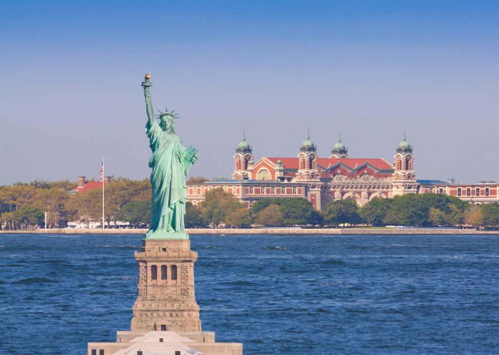 6 Reasons to Visit the Northeast Statue of Liberty, lit by morning sun, with Ellis Island in background, New York City. More than 12 million immigrants entered America through the golden door of Ellis Island. Canon EF 70-200mm f/4L IS lens.