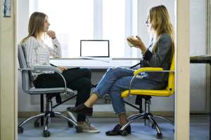 5 Traits to Look for in a Great Recruiter Young female employee discussing working details with her administrative executive during informal meeting in coworking office sitting near modern laptop computer with mock up screen connected to wifi