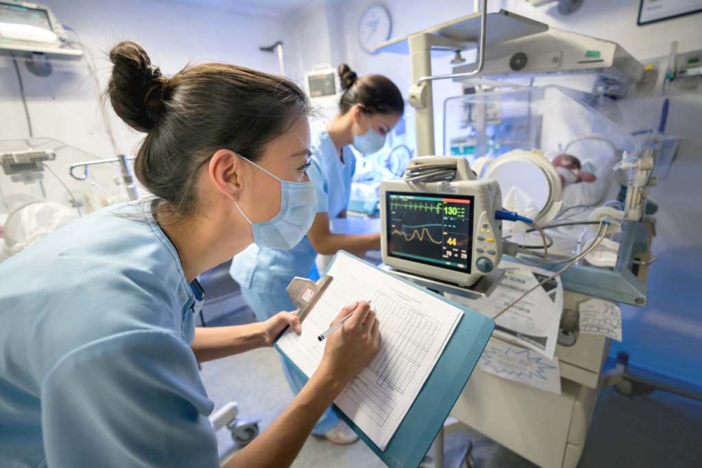 September Health Awareness Days 2022 Nurse monitoring a premature newborn in an incubator while wearing a facemask