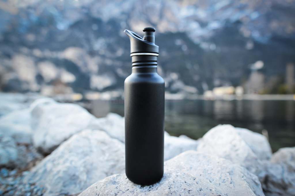 Best Gifts for Nurses and Allied Health Professionals Close-up black of steel eco thermo water bottle on the background of the lake in the mountains. Copy space. Zero waste, no plastic, sustainability.