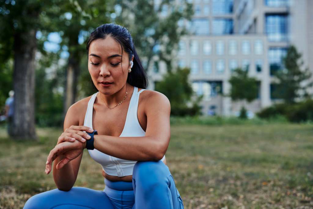Best Gifts for Nurses and Allied Health Professionals Female athlete setting up smart watch before workout in a forest. Beautiful asian sportswoman checking data on her gadget outdoor.