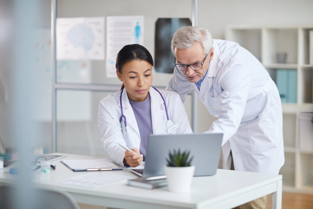 Two locum tenens doctors discussing a case over a laptop computer.
