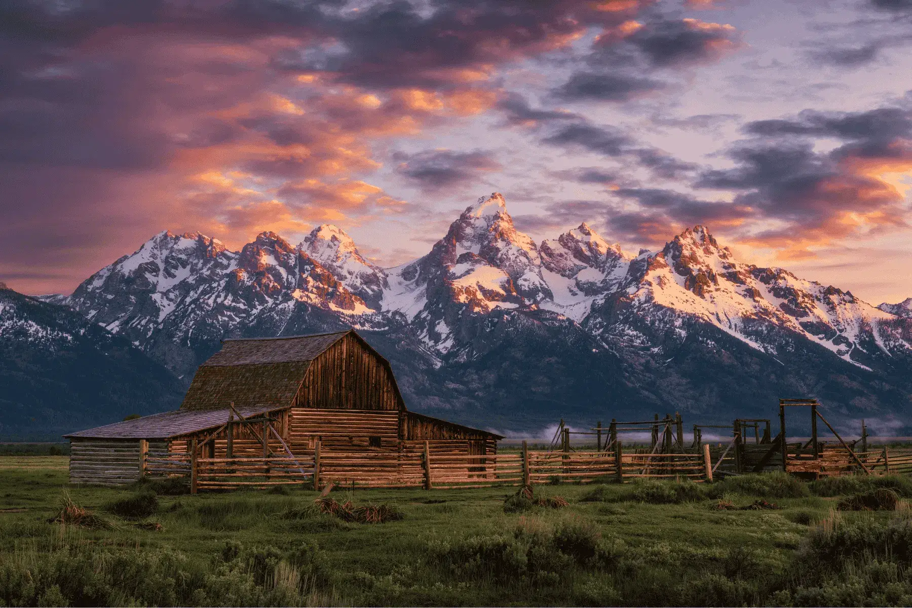 5 Mountainous National Parks and Top Hikes for the Best Views a picture of a barn with mountains in the background during sunset