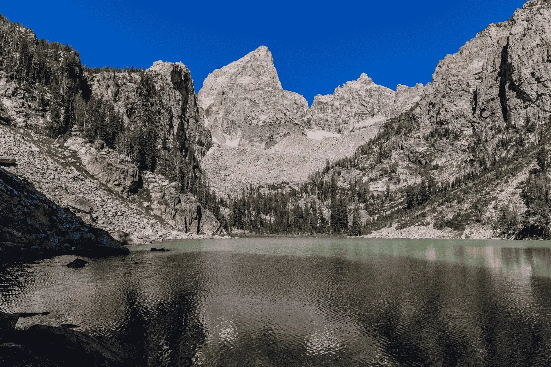 5 Mountainous National Parks and Top Hikes for the Best Views closeup view of a mountain with a lake below, surrounded by trees