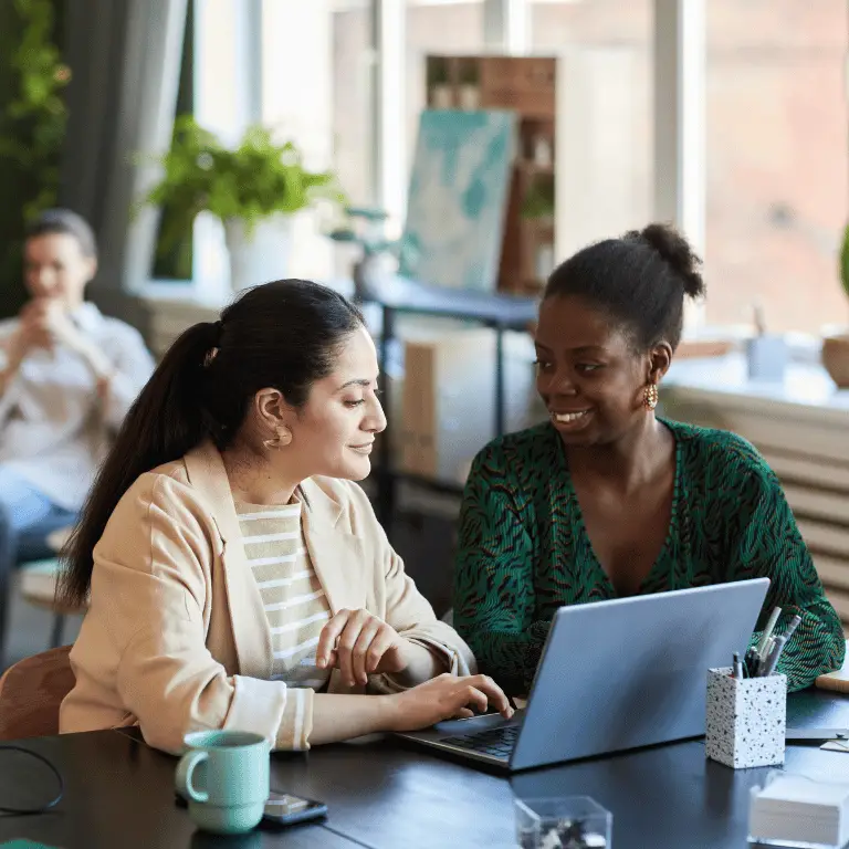 Two healthcare professionals collaborating on a laptop in a bright, modern office.