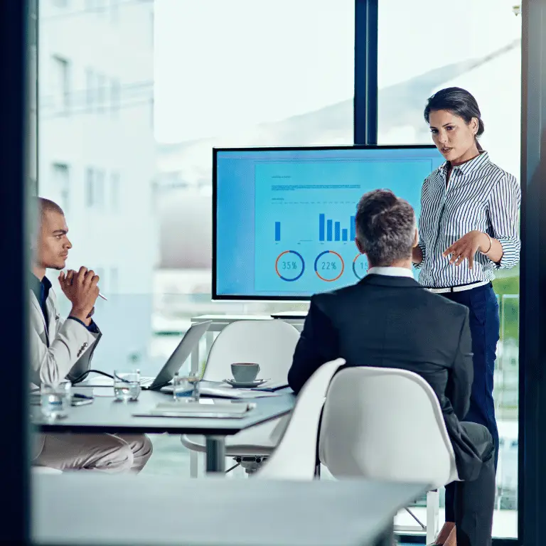 Business professional presenting performance data to colleagues during a team meeting.